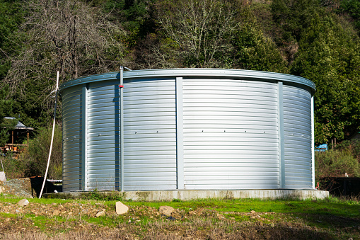 Large capacity corrugated steel water tank in rural neighborhood.