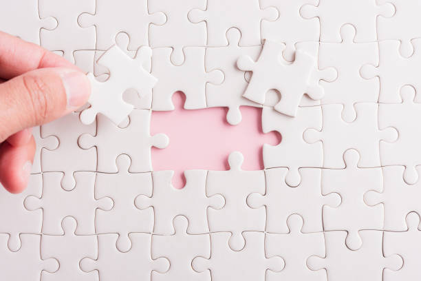 istock hand-holding last piece white paper jigsaw puzzle game last pieces 1302182250