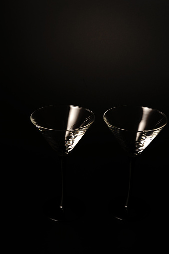Two empty cocktail glasses on a black background. Studio shooting. Dimmed lights