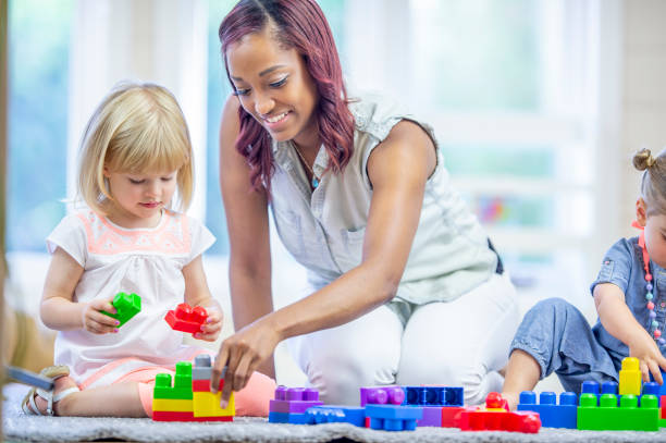 istock Preschool teacher playing with blocks with her students 1302192955