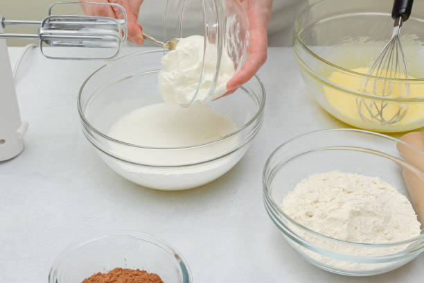 istock Close up baking process. Chef adds sour cream  into a bowl with whisked egg whites. 1302200966