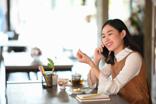 istock Cheerful young woman talking on mobile phone while siting in modern coffee shop. 1302203740