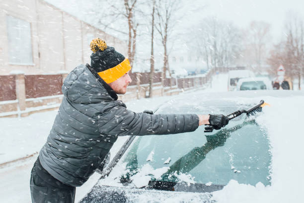 朝の冬の雪から車のブラシをブラッシングする男 - snow car window ice scraper ストックフォトと画像