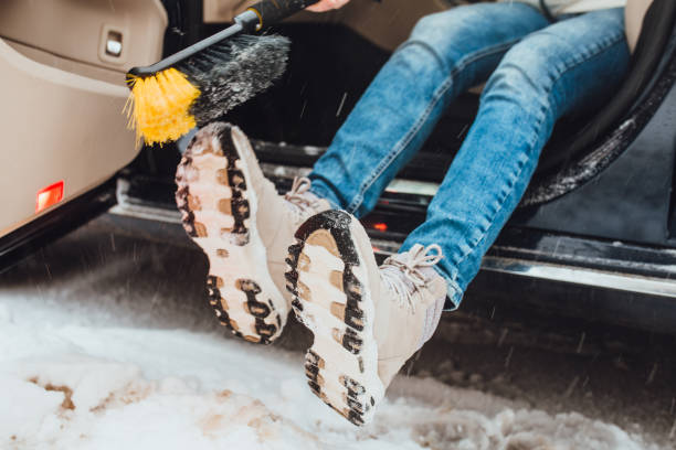 une femme nettoie la neige et frappe avec ses bottes pour secouer la neige et la saleté - snowshoeing snowshoe women shoe photos et images de collection