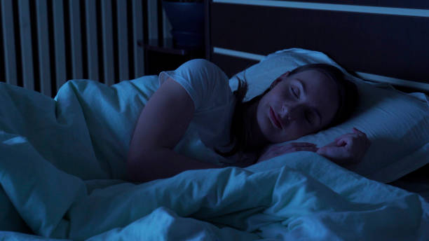 自宅のベッドで夜に快適に寝ている若い女性。睡眠時間 - comfortably ストックフォトと画像