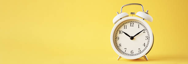 istock White vintage alarm clock on a yellow background, long banner with copy space 1302219950