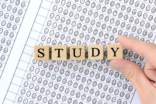 Human's hand picking wooden blocks with STUDY words on mark sheet