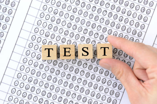 Human's hand picking wooden blocks with TEST words on mark sheet