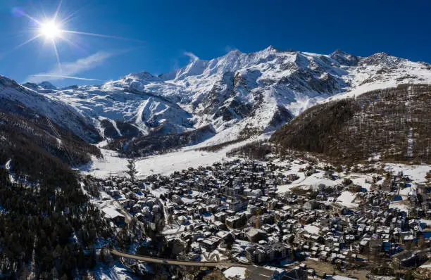 Aerial panorama of the famous Saas Fee village and ski resort by the Dom mountain, the tallest entirely in Switzerland in the alps on a sunny winter day