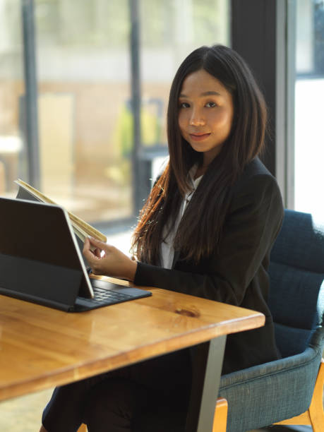 istock Businesswoman looking to camera while working with document file and digital tablet 1302227618