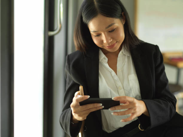 istock Businesswoman using horizontal smartphone while relaxing in cafeteria 1302227629