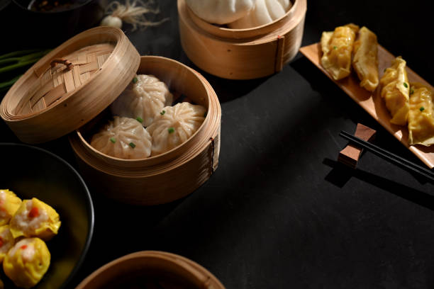 istock Dinning table in Chinese restaurant with Dinsum dumplings on bamboo steamer and chopstick 1302227774