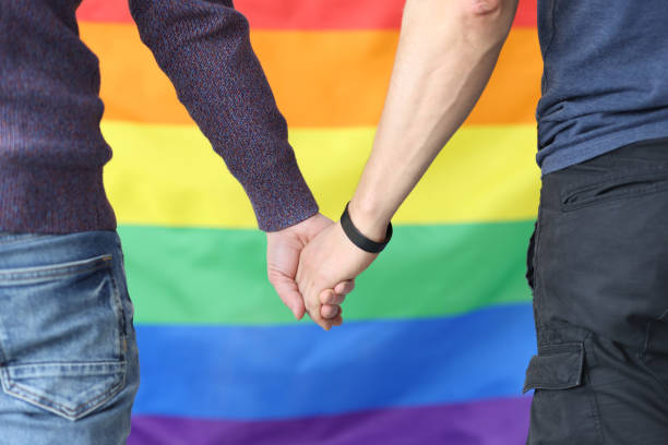 istock Young men holding hands with lgbt flag background closeup 1302230827