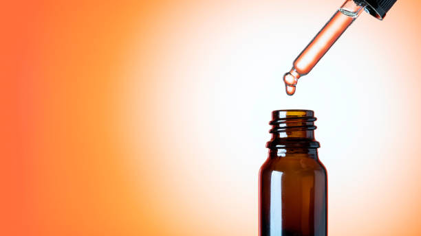 istock Oily drop falls from a cosmetic pipette, isolated on orange background 1302231316