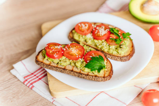 istock toasted bread with avocado paste and fresh tomato. Avocado mixed with lemon juice is spread on bread.  health food concept, vegan, vegetarian 1302232153