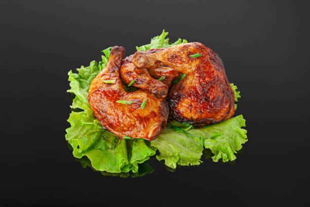 istock Grilled chicken legs on a lettuce leaf. Decorated with greenery. Close-up. Dark mirror background. 1302232306