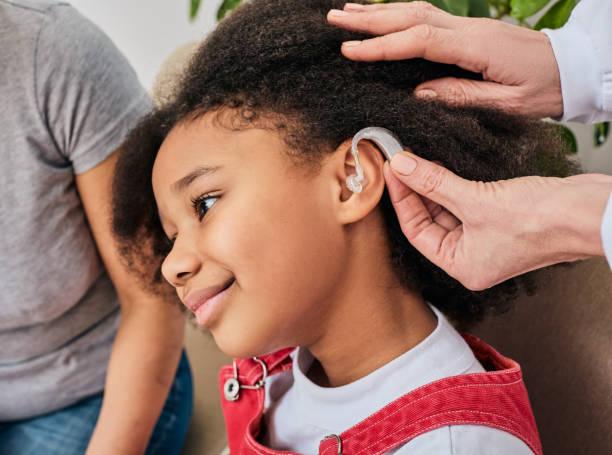 hörlösungen für kinder. arzt installiert hörgerät am ohr des afroamerikanischen mädchens, nahaufnahme - hearing aid audiologist audiology small stock-fotos und bilder