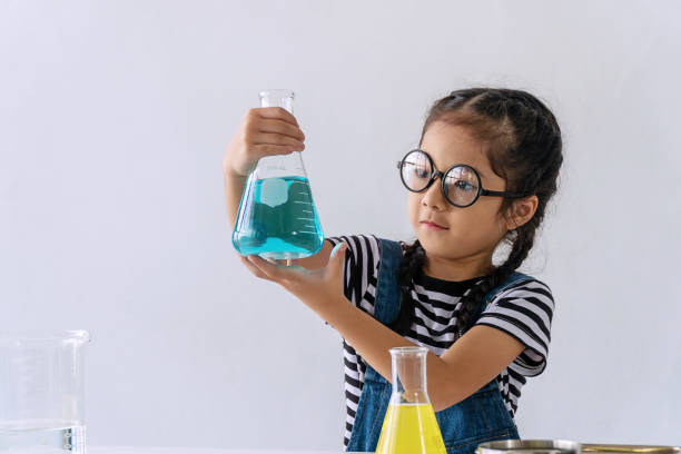istock Little 6s cute girl with microscope holding laboratory bottle with water experiment study scientists at school. Education science concept. 1302232619