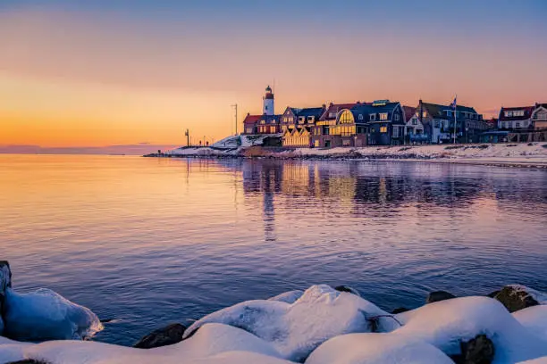 Photo of Winter in Urk with the dike and beach by the lighthouse of Urk snow covered during winter, sunset by the lighthouse of Urk Flevoland