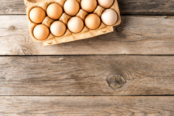 istock Chicken eggs in box on wooden table with copyspace. Top view 1302235258