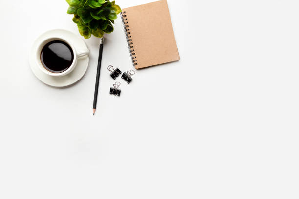 istock Flat lay, top view office table desk. Workspace with blank, office supplies, pencil, green leaf, and coffee cup on white background. 1302235363