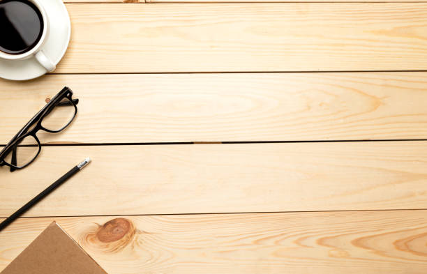 istock Top view office table desk. Workspace with blank, office supplies, pencil, green leaf, and coffee cup on wood background. 1302235931