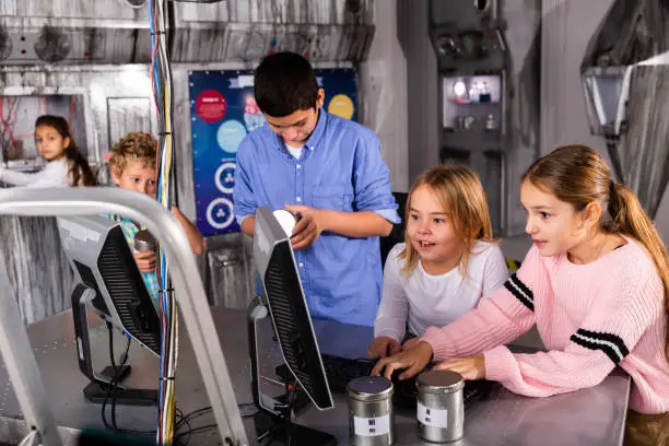 Photo of Interested tweens using computer in escape room bunker