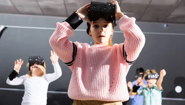 Photo of Tween girl using vr headset goggles to play exciting game