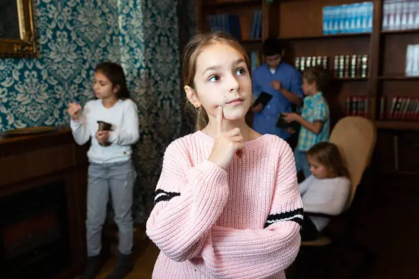 Photo of Pensive tween girl trying to find solution of conundrum in quest room