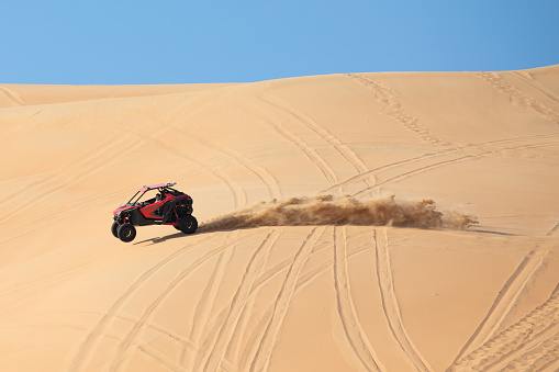 Liwa desert, Abu Dhabi, UAE - Feb 12, 2021: Dune buggy doing jumping tricks in the desert on a sunny day.