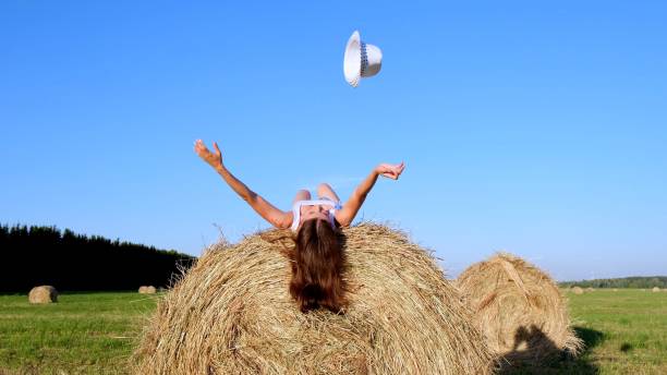 istock young female lies on a haystack and throws his hat. Rural area. freedom concept 1302240523