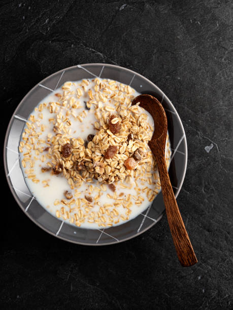 farina d'avena, fiocchi d'avena in ciotola, colazione sana con farina d'avena, farina d'avena e sfondo nero - oat oatmeal rolled oats oat flake foto e immagini stock