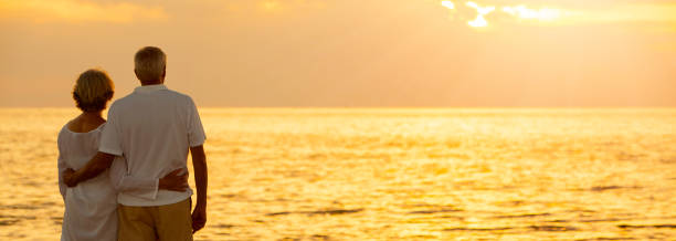 panorama casal de idosos e mulheres abraçando ao pôr do sol ou nascer do sol em uma praia tropical deserta panorâmica web banner - retirement sun sunset senior adult - fotografias e filmes do acervo