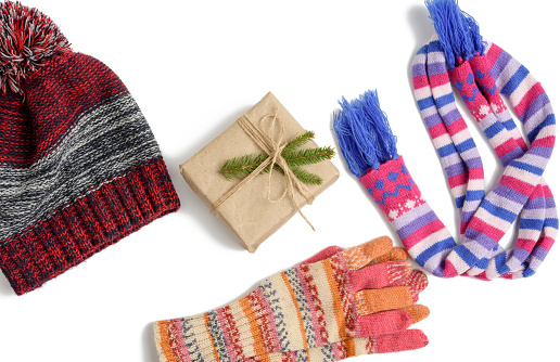 winter hat, gift box and multicolored knitted scarf on a white background, a set on a white background, top view