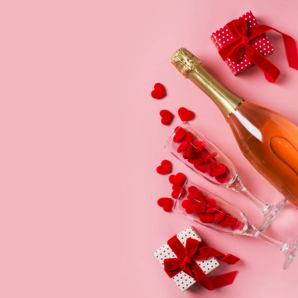 istock Two glasses with red hearts and gift flat lay on pink background 1302248627