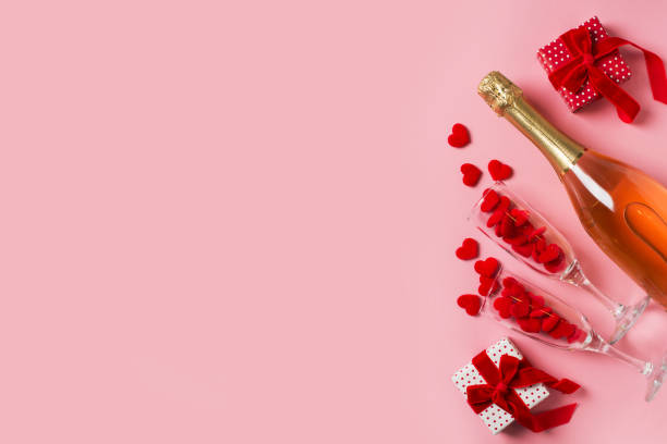 istock Two glasses with red hearts and gift flat lay on pink background 1302248629