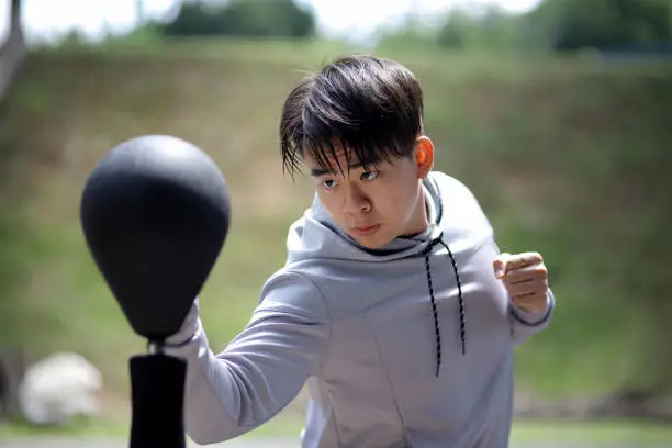 An Asian young man is training outdoor boxing during leisure time.