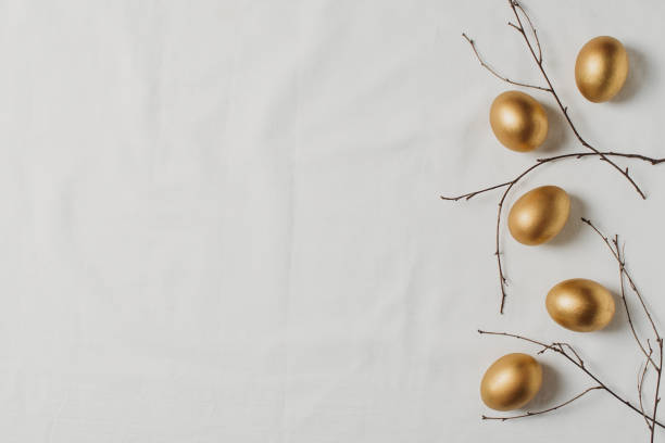 istock Easter concept with golden eggs and twigs flat lay on white texture background 1302249303