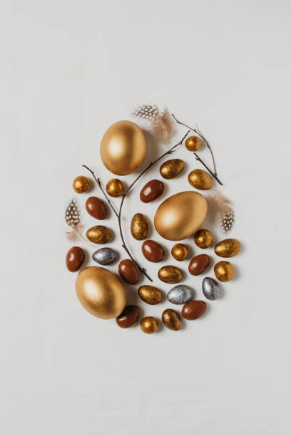 istock Easter concept with golden eggs and twigs flat lay on white texture background 1302249308