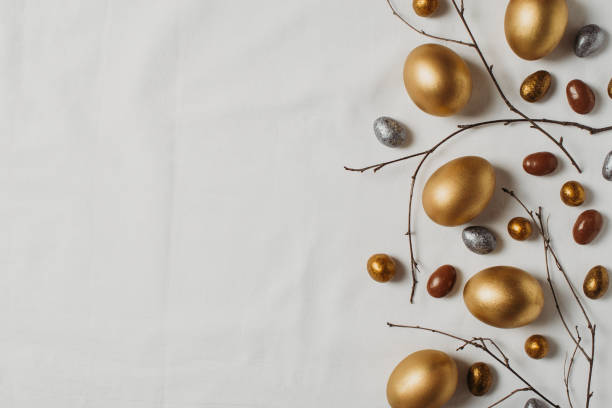 istock Easter concept with golden eggs and twigs flat lay on white texture background 1302249311
