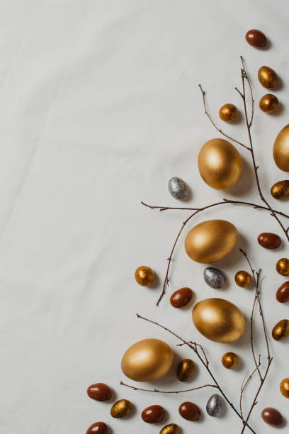 istock Easter concept with golden eggs and twigs flat lay on white texture background 1302249325