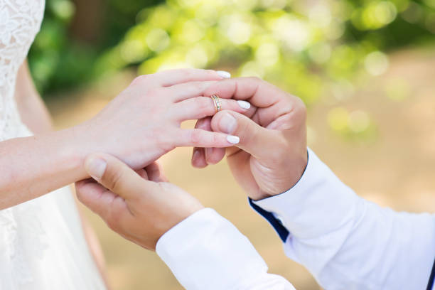 istock The groom puts the wedding ring on the bride's finger 1302250033