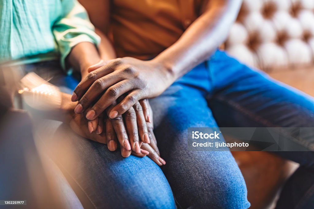 Together we'll make it better Closeup shot of an unrecognizable couple holding hands while sitting on sofa during the day. Addiction Stock Photo