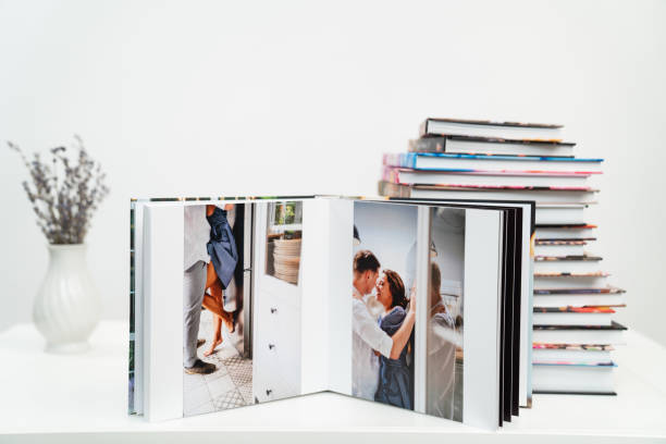 stack of books. open photobook from photo shoots of a beautiful happy couple stack of books. open photobook from photo shoots of a a beautiful happy couple in the kitchen. grainy paper texture. photo design in the album. Memory. Designer. white background honeymoon book stock pictures, royalty-free photos & images