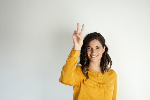 portrait of a smiling young woman holding up two fingers isolated on white background