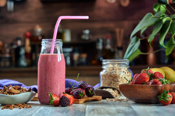 istock Healthy food: Banana and blackberry yogurt smoothie with cereal in bottle with straws on a rustic table. 1302254582