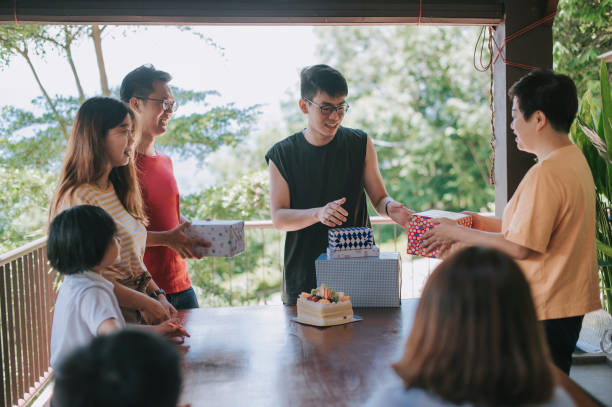 asian chinese man receiving birthday present celebrating his birthday with friends and family at backyard of house during weekend asian chinese man receiving birthday present celebrating his birthday with friends and family at backyard of house during weekend happy birthday cousin images stock pictures, royalty-free photos & images