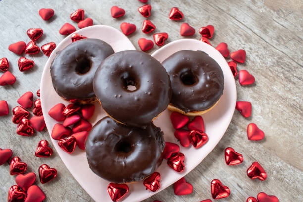 istock chocolate covered doughnuts on heart shaped plate surrounded by Valentine hearts 1302255802