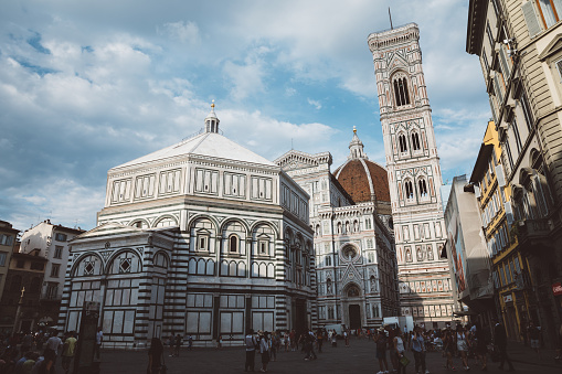 Florence, Italy - June 24, 2018: Panoramic view of Duomo complex: Baptistery of Saint John, Cattedrale di Santa Maria del Fiore and Giotto's Campanile. People walk on Piazza del Duomo in summer day