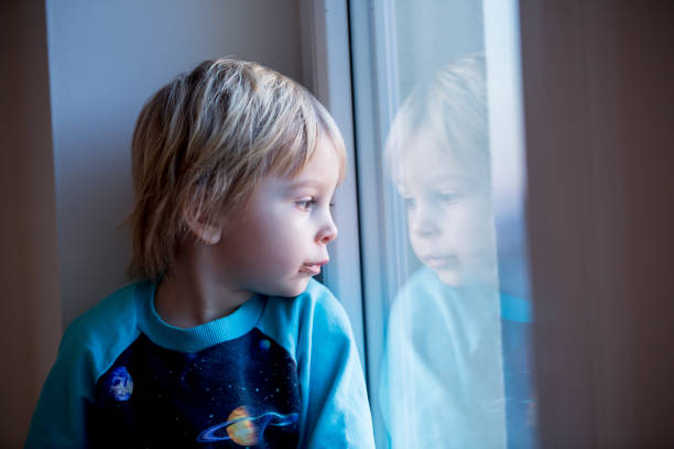 istock Toddler child, sitting on the window on sunset 1302256368